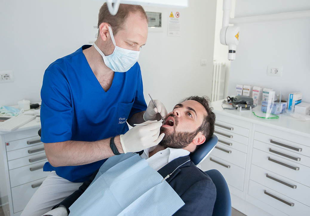 Dentista a Concorezzo: Dentista che visita paziente in giacca e camicia