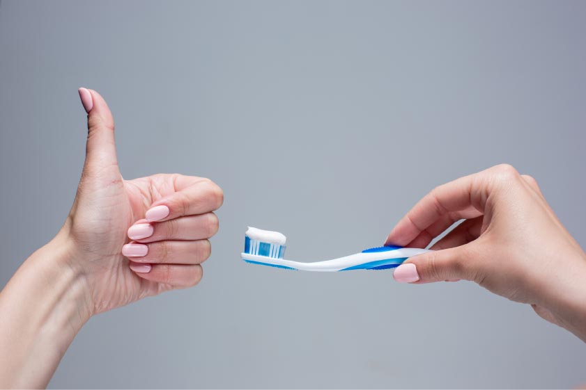 prevenzione dentale: mano che yes e mano che sostiene lo spazzolino